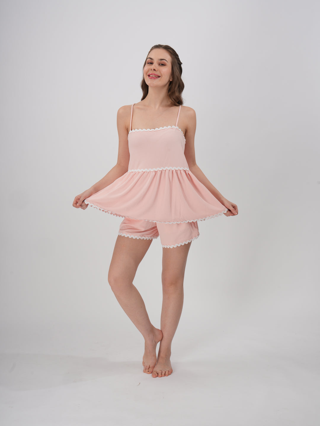 A woman wearing a blush pink loungewear set with a flowy Cami top and matching shorts - Blush Pink Wave Short Set