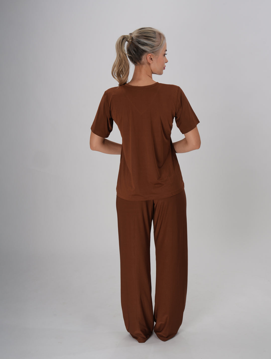 A Woman wearing a brown V-neck, short sleeve T-shirt and mid-rise pants with an elastic waistband - Coffee Crush PJ Set.