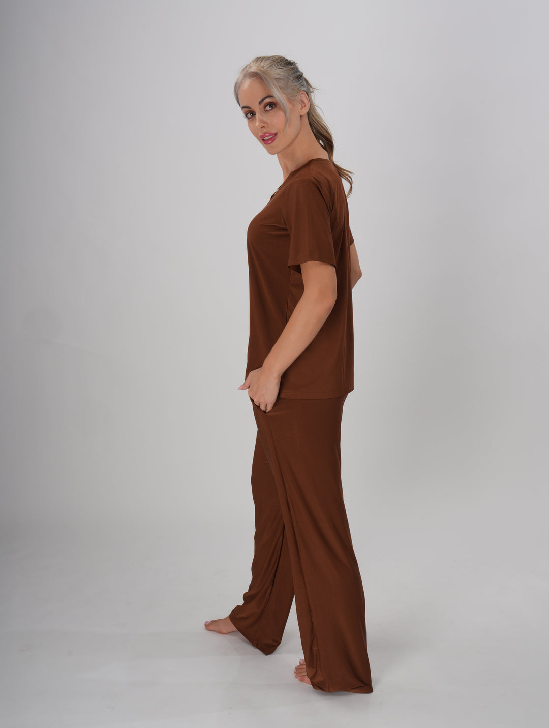 A Woman wearing a brown V-neck, short sleeve T-shirt and mid-rise pants with an elastic waistband - Coffee Crush PJ Set.