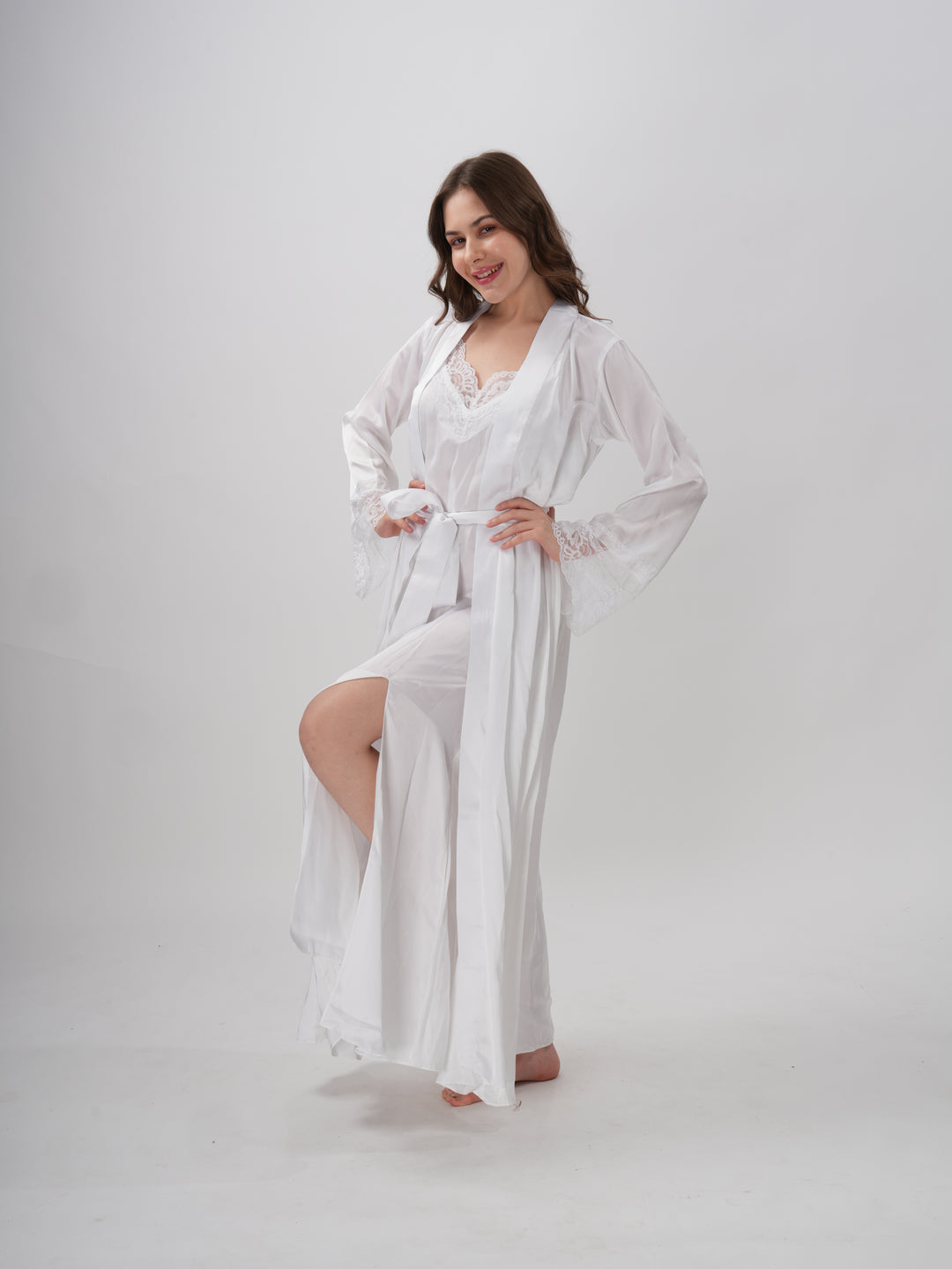 A woman standing wearing a white, full-length robe with lace detailing on the sleeves and neckline - Ethereal Grace Robe Set