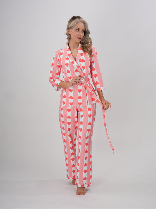 A model wearing a pink hearts pajama set with a collar and full sleeves. The set includes a detachable belt -Hearts & Hush PJ Set