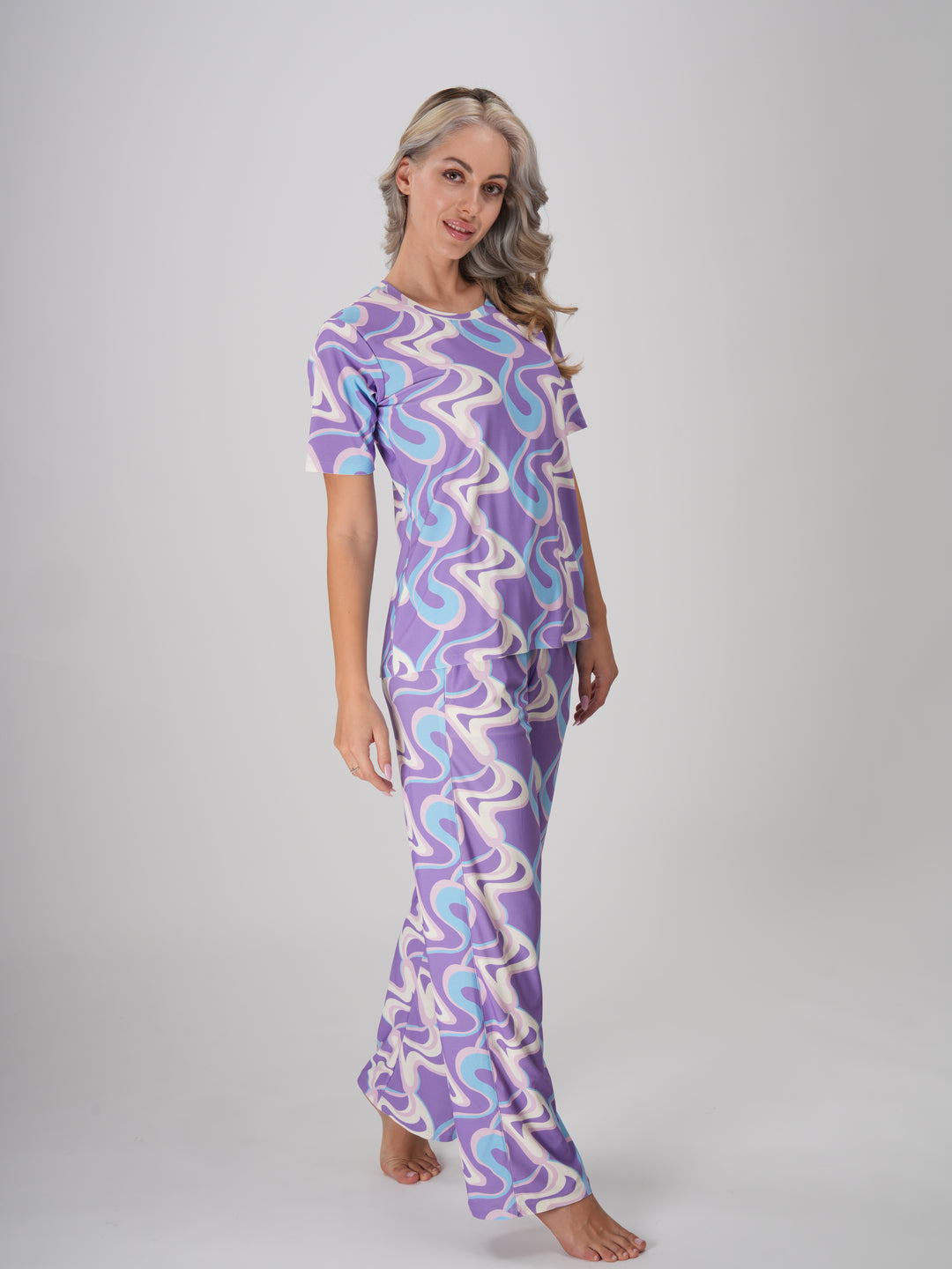 A woman in a lavender twirls pajama set with a swirl pattern in shades of lavender, ivory, and sky blue - Lavender Twirls PJ Set