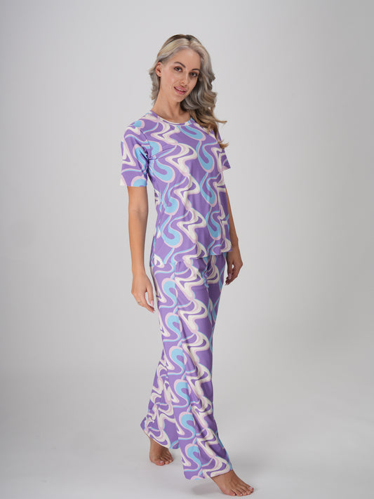A woman in a lavender twirls pajama set with a swirl pattern in shades of lavender, ivory, and sky blue - Lavender Twirls PJ Set