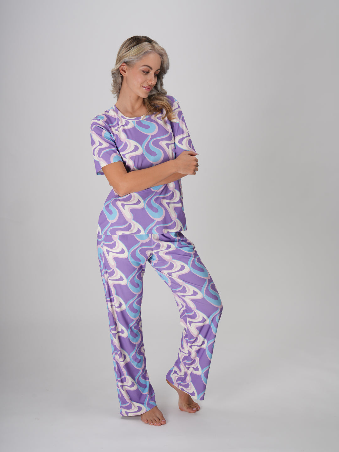 A woman in a lavender twirls pajama set with a swirl pattern in shades of lavender, ivory, and sky blue - Lavender Twirls PJ Set