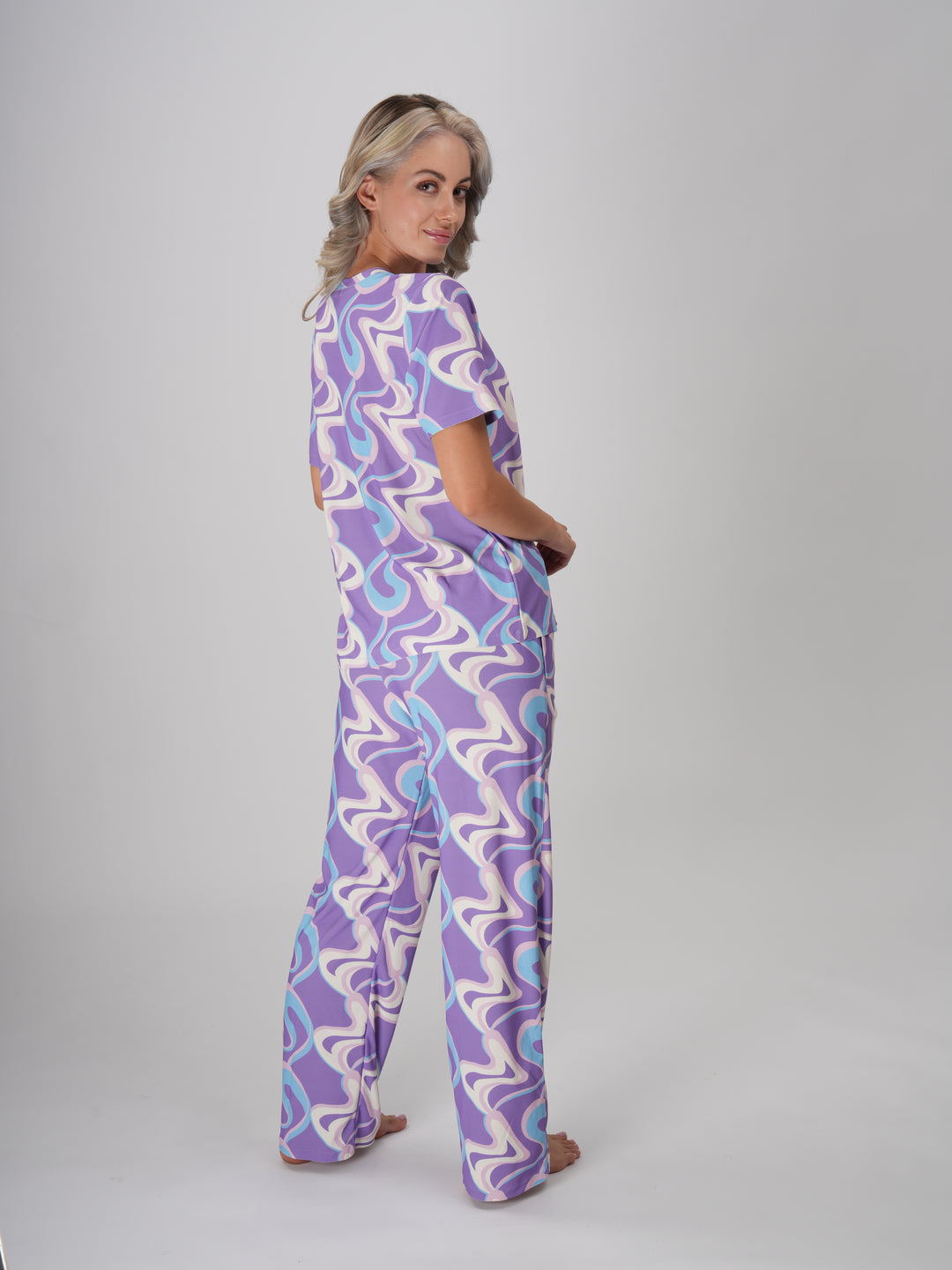 A woman in a lavender twirls pajama set with a swirl pattern in shades of lavender, ivory, and sky blue - Lavender Twirls PJ Set