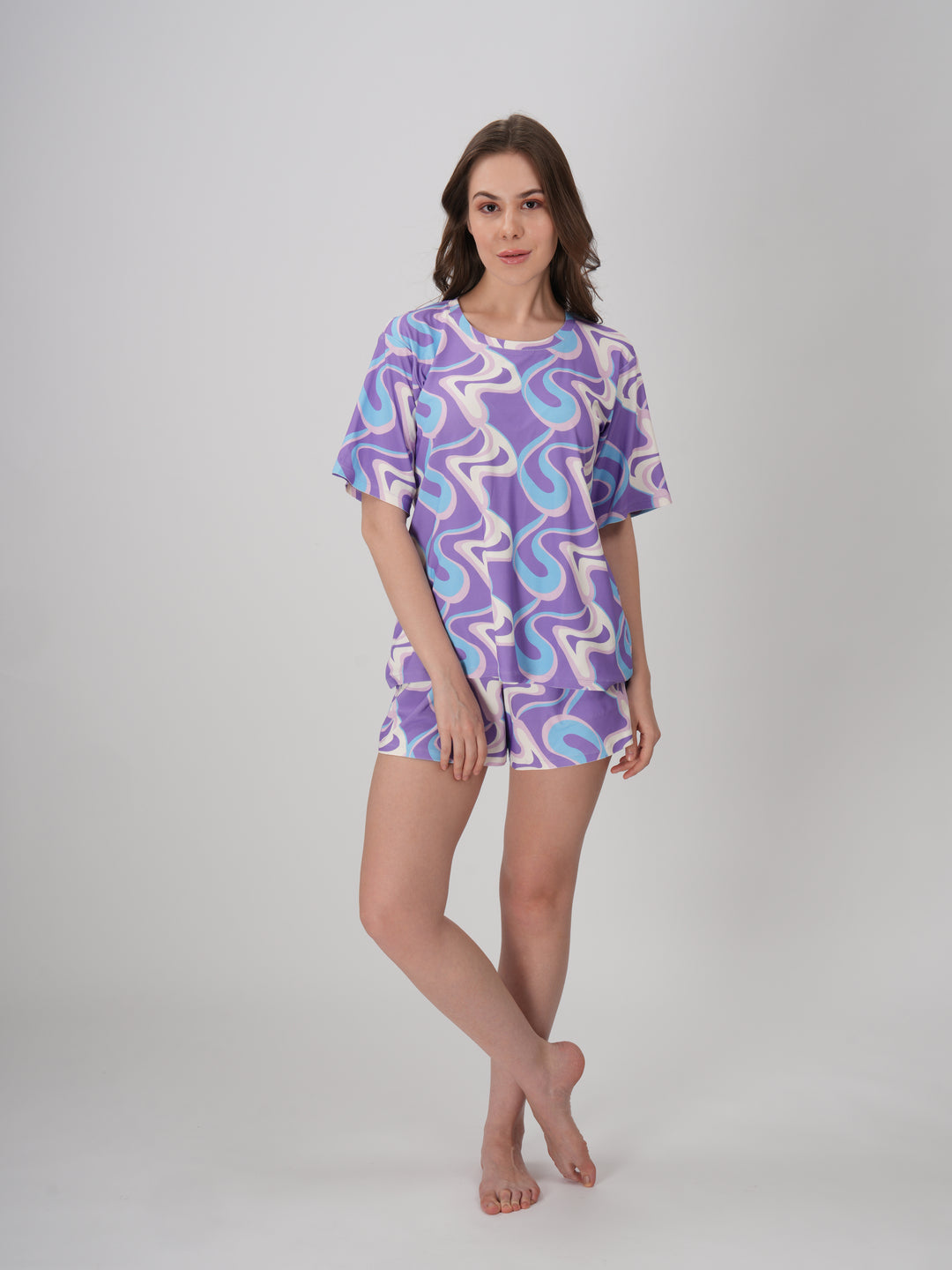 A model wearing a lavender and blue geometric patterned short set with a slim fit top and mid-rise pajama shorts - Lavender Twirls Short Set.