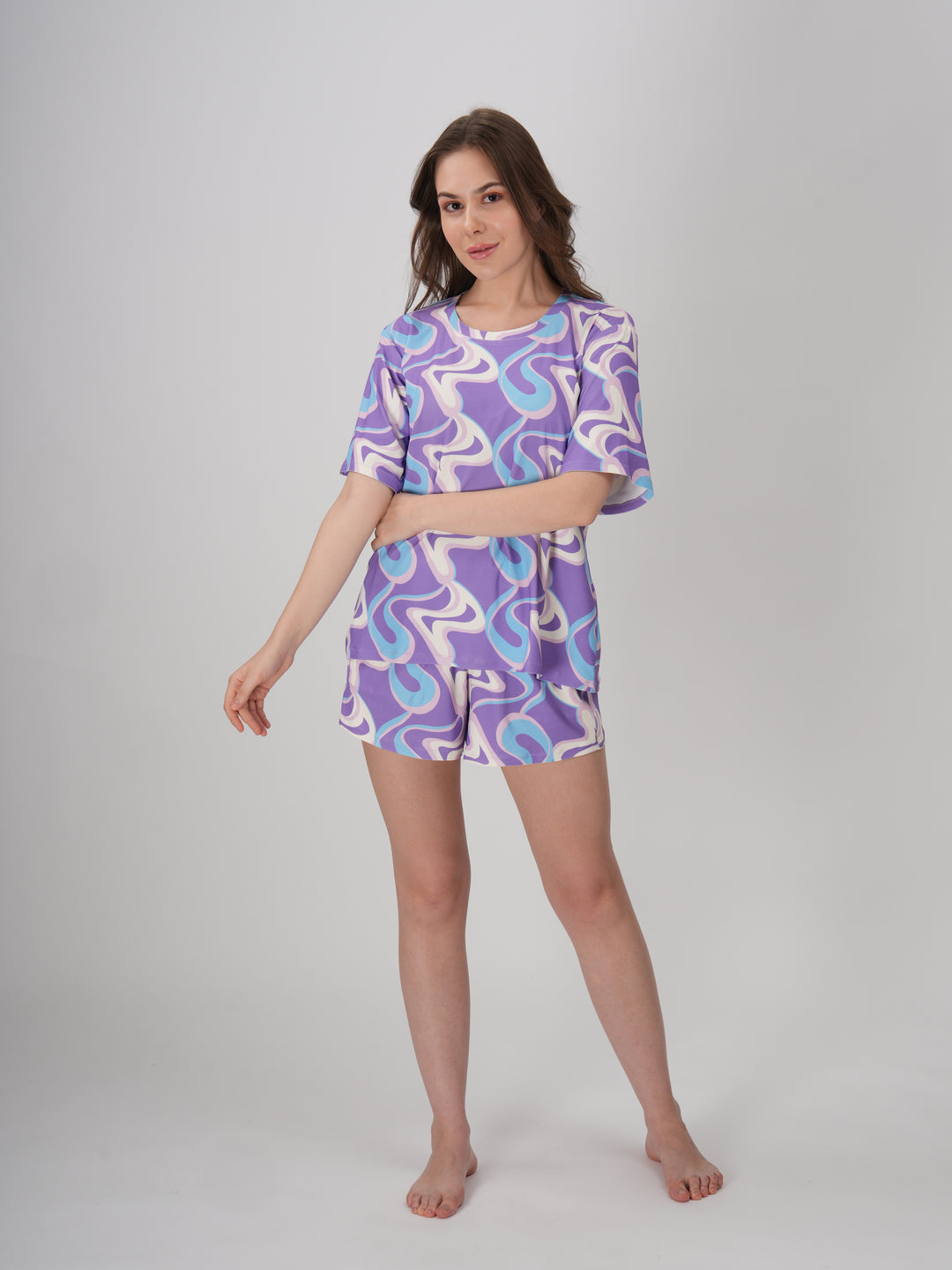 A model wearing a lavender and blue geometric patterned short set with a slim fit top and mid-rise pajama shorts - Lavender Twirls Short Set.