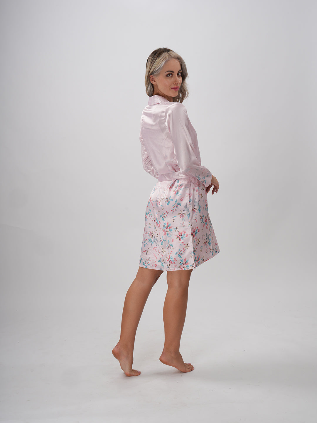 A woman wearing a pink floral robe with a round neckline and a sash belt - Mystical Bloom Robe