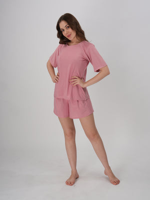 A woman standing, wearing a pink short set with mid-rise shorts with an elastic waistband - Petal Push Short Set