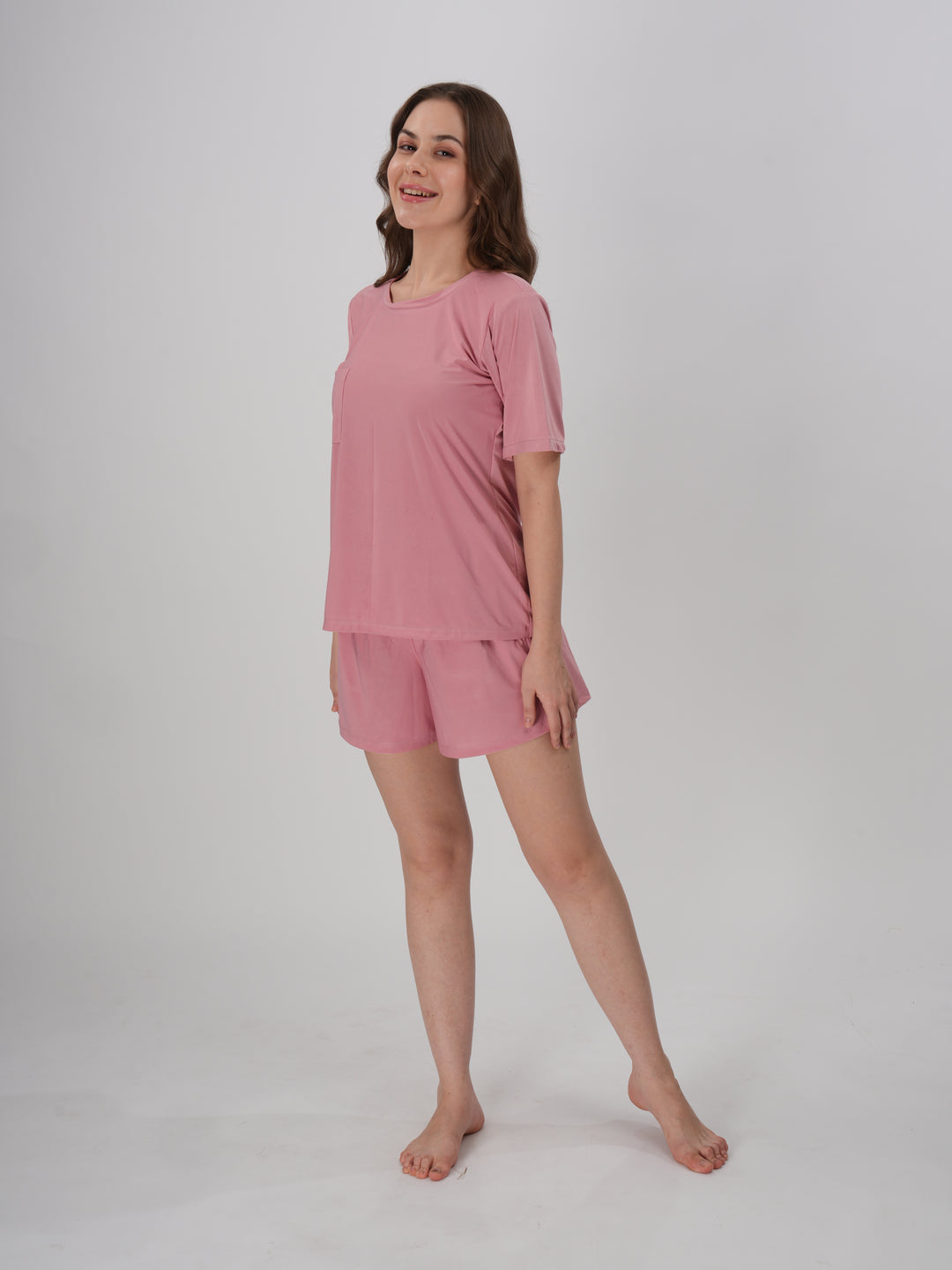 A woman standing, wearing a pink short set with mid-rise shorts with an elastic waistband - Petal Push Short Set