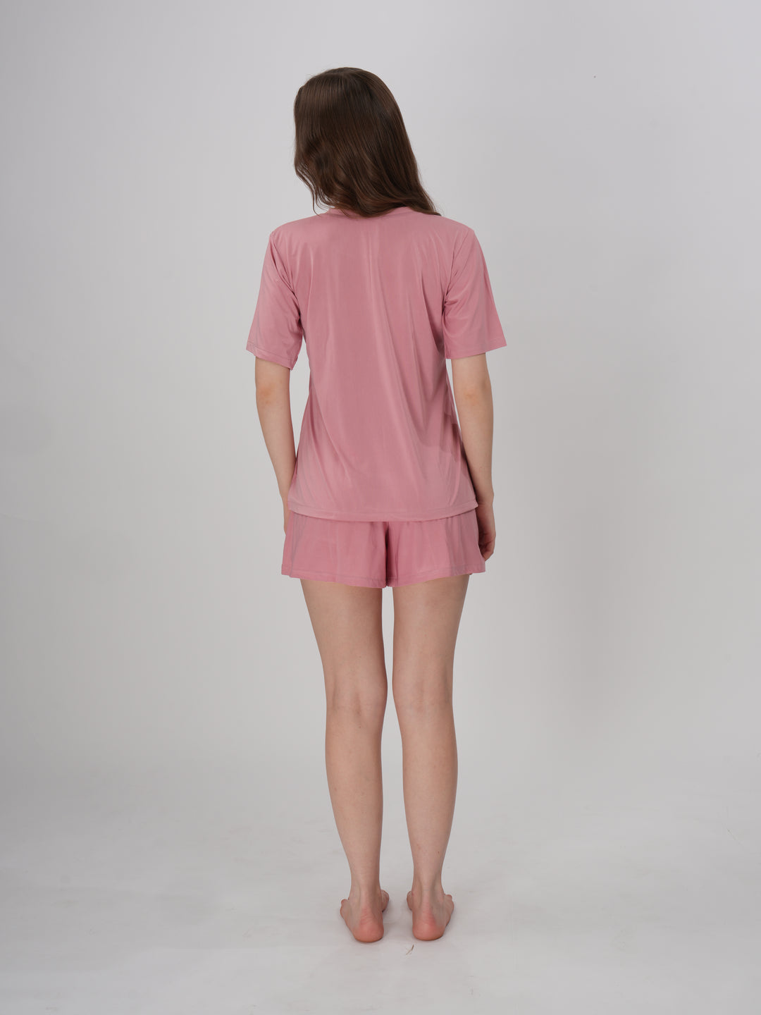 A woman standing, wearing a pink short set with mid-rise shorts with an elastic waistband - Petal Push Short Set