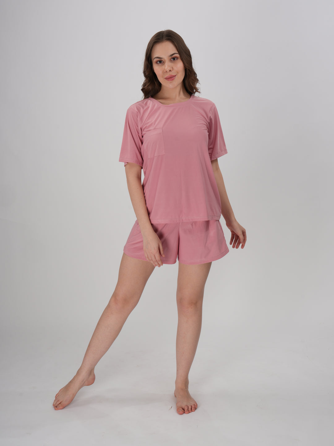 A woman standing, wearing a pink short set with mid-rise shorts with an elastic waistband - Petal Push Short Set