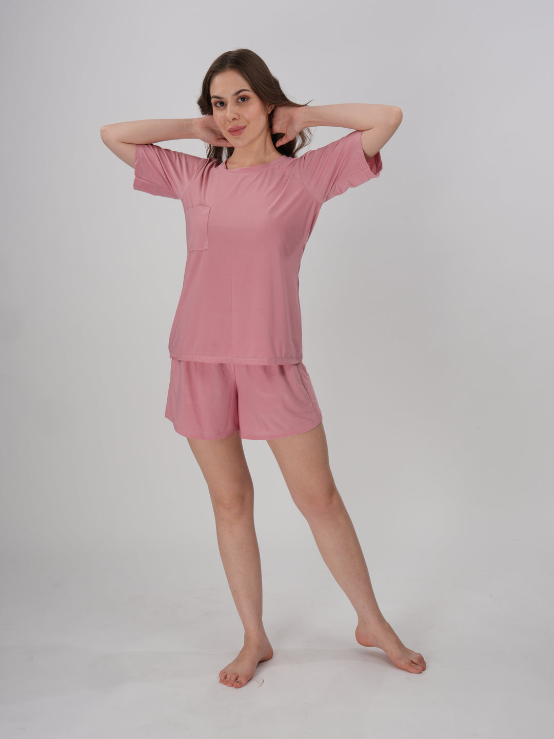 A woman standing, wearing a pink short set with mid-rise shorts with an elastic waistband - Petal Push Short Set