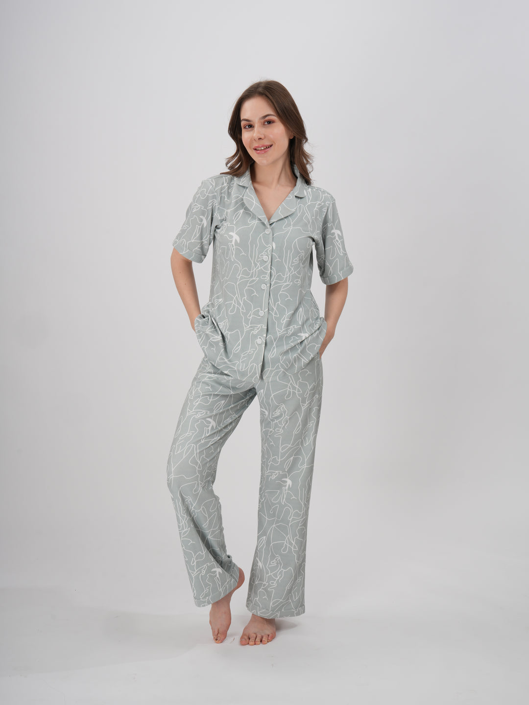 A woman standing, wearing a short-sleeved, full-length pajama set with an abstract line print - Serene Lines PJ Set