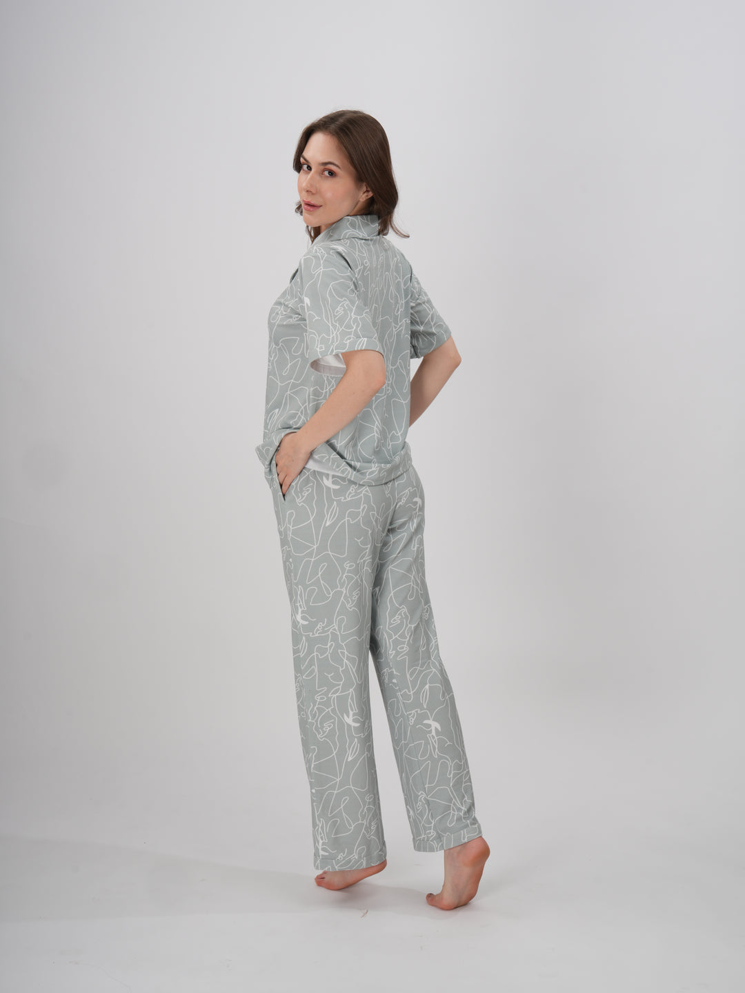 A woman standing, wearing a short-sleeved, full-length pajama set with an abstract line print - Serene Lines PJ Set