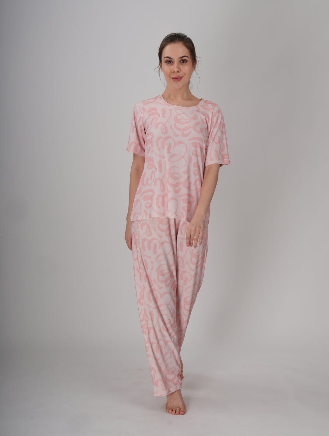 A woman standing, wearing a short pink PJ set with a round neckline and elastic waistband - Soft Pink Seam PJ Set.