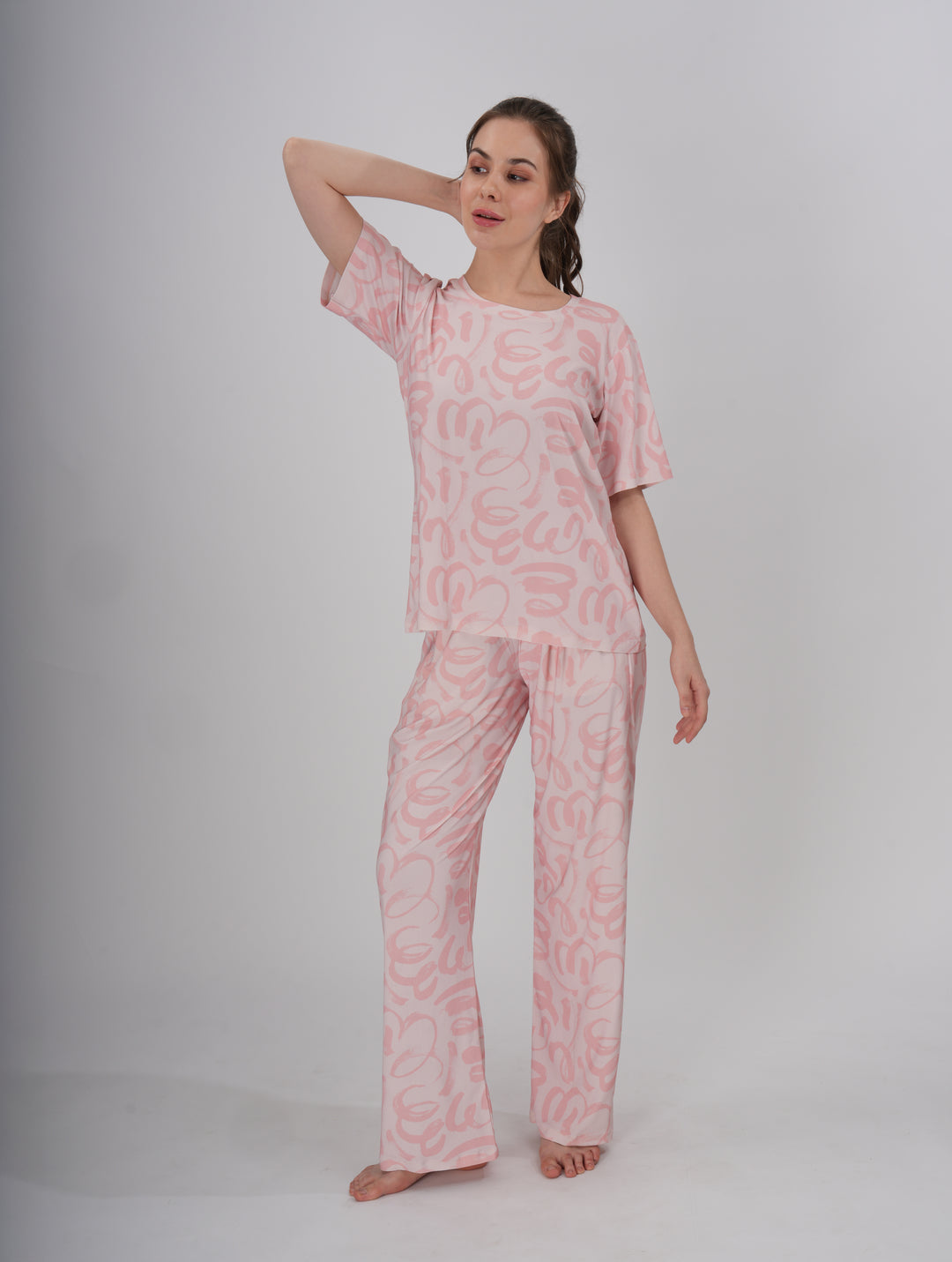 A woman standing, wearing a short pink PJ set with a round neckline and elastic waistband - Soft Pink Seam PJ Set.