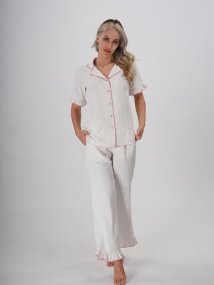Woman wearing a white pajama set with ruffle trim, classic collar, and button-down top – Sweet Dreams PJ Set