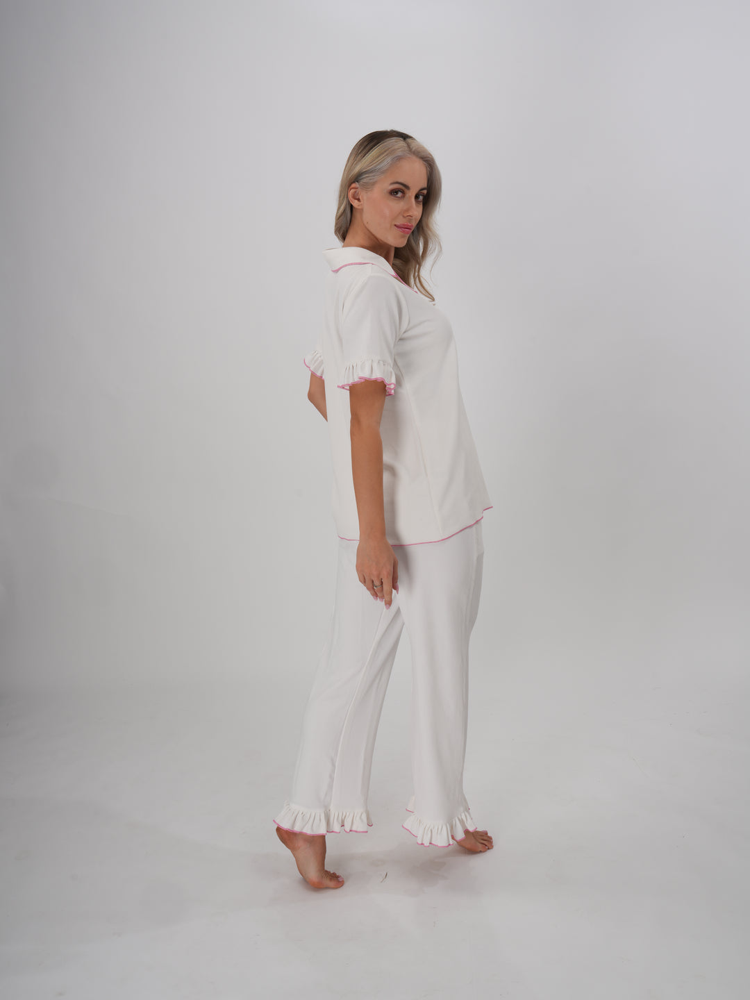 Woman wearing a white pajama set with ruffle trim, classic collar, and button-down top – Sweet Dreams PJ Set