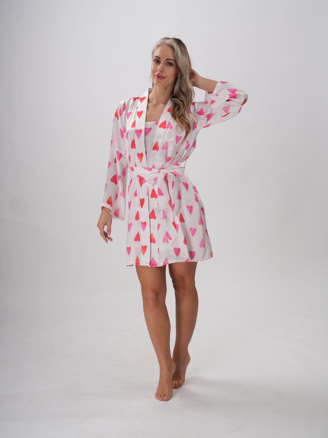 Woman wearing a pink and white robe with all-over heart print, V-neckline, and adjustable waist tie – Sweetheart Robe